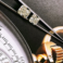 Close Up of Tweezers Holding Two Polished Diamonds with a Watch at the Background