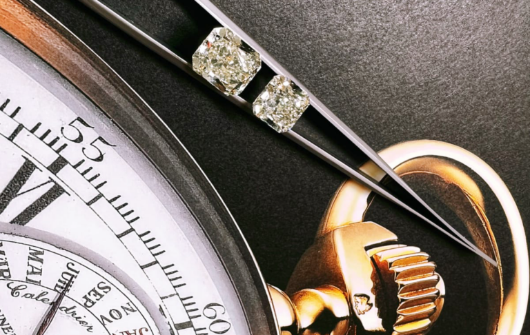 Close Up of Tweezers Holding Two Polished Diamonds with a Watch at the Background